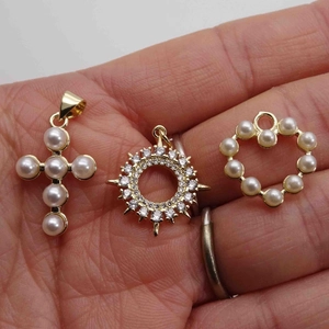 Golden heart, cross and star pendants with pearls and rhinestones held in hand