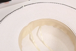 Detail of white straw hat interior featuring adjustable ribbon and soft sweatband texture