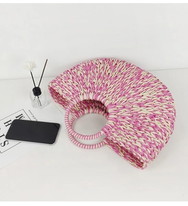 Flat lay of pink and beige woven straw tote bag with aromatherapy bottle and magazine