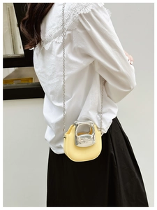 Close-up of yellow mini crossbody bag with silver metal handle and chain strap on model