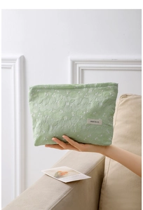Close-up of light green cosmetic bag with white lace floral embroidery and brand label