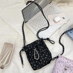 Lifestyle shot of floral quilted crossbody bag with drawstring and daily essentials