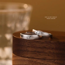 Macro shot of S999 silver couple rings with cartoon engraving on a wooden base