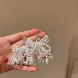 Detailed view of lace bow earrings featuring hanging pearl tassels and crystal beads