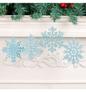 Blue glitter snowflake ornaments hanging on a white festive mantle with green garland