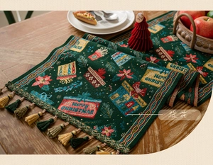 Detail of Christmas table runner featuring green jacquard gift patterns and festive tassels