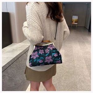 Detail of a black embroidery handbag with purple 3D flowers and a bamboo handle