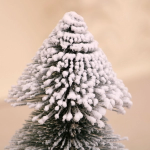 Macro shot of snow-covered green pine needles on a tabletop Christmas tree ornament
