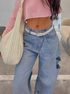 Jeans da donna azzurri a gamba larga strappati abbinati a felpa corta rosa e borsa bianca