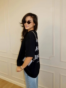 Oversized black graphic T-shirt with drop shoulders styled with denim jeans and chain bag