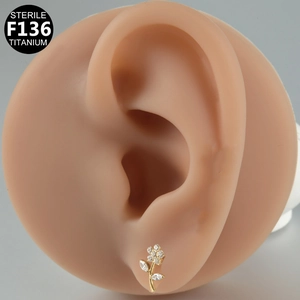 Macro view of gold titanium flower ear stud with cubic zirconia on a model ear