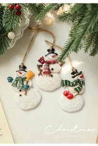Detailed view of hand-painted resin snowman ornaments with festive pine and lights