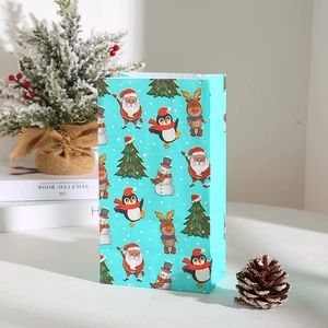 Close-up of light blue Christmas paper gift bag featuring penguin and reindeer patterns