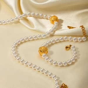 Détail d'un ensemble collier et bracelet en perles avec billes dorées sur soie beige