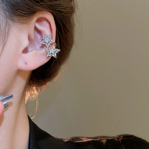 Close-up of silver-plated star ear cuff with cubic zirconia on model's ear cartilage