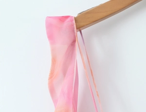 Dettaglio dell'abito in chiffon sfumato rosa e arancione con spalline sottili