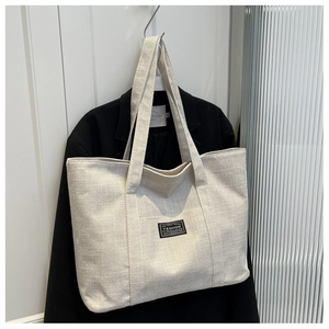 Detail of canvas tote bag with FASHION label hanging on a black blazer jacket