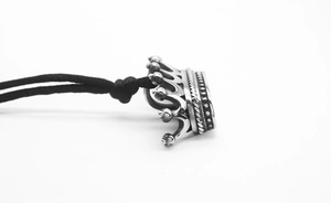 Macro view of vintage silver crown pendant with beaded details on black cord