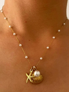 Close-up of ocean-themed necklace with gold starfish, shell charms, and white pearls