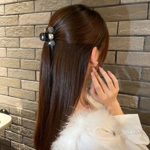 Close-up of model wearing a stylish pearl and rhinestone hair claw clip on brick background