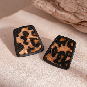 Macro detail of geometric leopard print earrings with fuzzy flocking texture and black frame