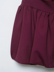 Détail d'une mini-robe ballon bordeaux montrant le tissu plissé et la silhouette bouffante