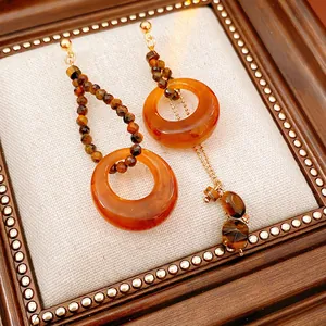 Vintage asymmetric earrings with amber resin beads and gold accents on a white textured background