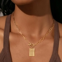Detail of gold rectangular cross pendant with paperclip chain and toggle clasp