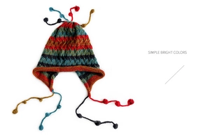 Detail of colorful striped knitted earflap hat with decorative pom-pom tassels