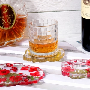 Handmade clear resin coasters with embedded real dried flowers on white wooden surface