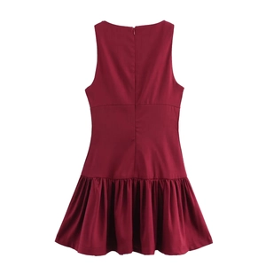 Detail view of burgundy sleeveless dress featuring a back zipper and pleated hem design