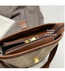 Close-up of smooth gold zipper and buckle detail on a canvas bucket bag with leather trim