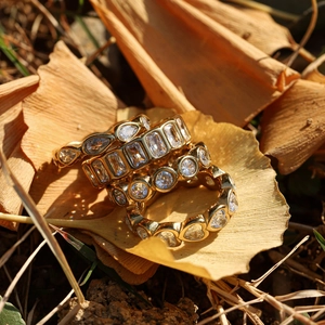Set of four gold heart and emerald cut zircon rings on autumn ginkgo leaves