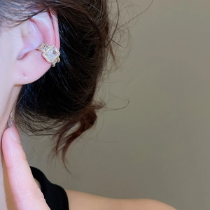 Detail shot of a golden ear cuff with emerald-cut zircons worn on the upper ear cartilage