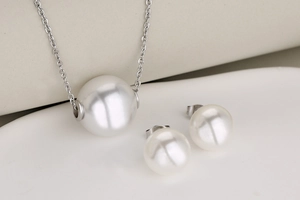 Detailed view of white pearl pendant necklace and matching stud earrings set