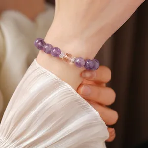 Elegant amethyst bead bracelet with a faceted crystal center on a female wrist