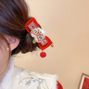 Detail of red velvet lion dance hair clip with golden coins and festive bell tassels
