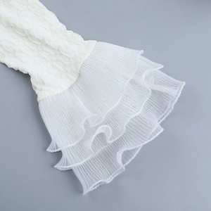 Close-up of white crinkled fabric texture and layered mesh ruffle details on dress