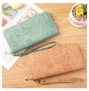 Detail of floral embossed leather long wallets in mint green and peach with wrist straps