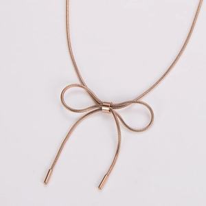 Detail of rose gold bow necklace featuring a sleek snake chain and elegant pendant drop