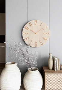 Modern wall clock detail featuring natural wood grain dial with metallic copper numerals
