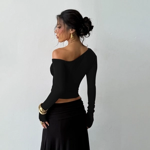 Macro shot of the asymmetric shoulder cutout and slim fit sleeve design on black top