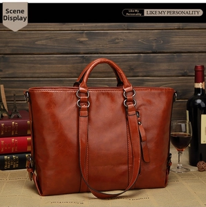 Dettaglio della borsa tote in pelle cerata marrone con fibbie regolabili e finiture in bronzo