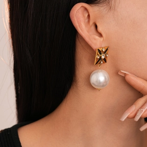 Macro shot of vintage gold earrings with black enamel star, crystals and large pearls