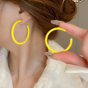Close-up of vibrant yellow hoop earrings worn by a model showcasing minimalist style