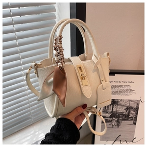 Détail du sac seau en cuir blanc crème avec fermoir doré et poignée en ruban de soie