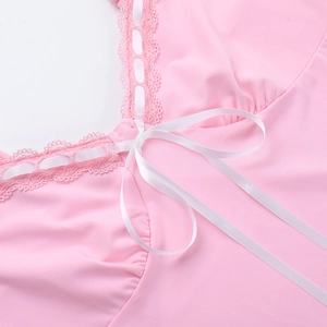 Dettaglio del tessuto rosa a maglia con pizzo delicato e un fiocco in nastro di raso bianco