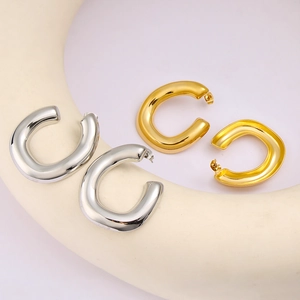 Detail view of thick C-shaped hoop earrings in polished gold and silver finishes