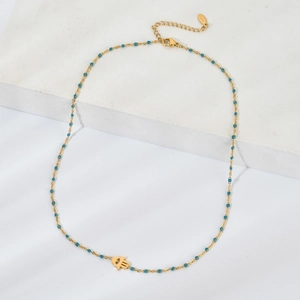 Détail d'un collier doré perlé avec pendentif main de Hamsa sur présentoir