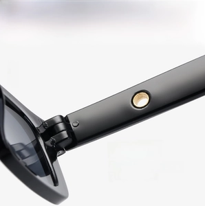 Macro detail of high-gloss black eyewear hinges with reinforced metal ring structure